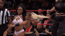 two women in a wrestling ring with a referee behind them