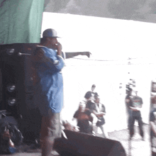a man in a blue shirt is standing on a stage with a microphone in his mouth