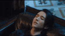 a man with long black hair is laying on a couch with his eyes closed