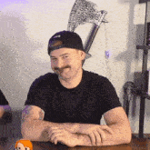 a man with a hat that says axe on it sits at a table