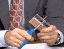 a man in a suit and tie is cutting a credit card with a pair of scissors