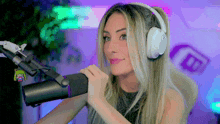 a woman wearing headphones stands in front of a microphone with the letter b behind her