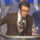 a man in a suit and tie is giving a speech in front of a microphone