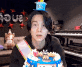 a young man wearing a birthday hat is holding a birthday cake