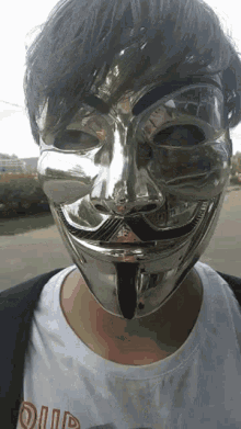a man wearing a silver anonymous mask and a t-shirt that says ' oiup ' on it