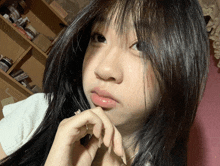 a girl with long black hair is taking a selfie in front of a shelf full of medicines