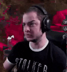 a man wearing headphones and a black shirt is sitting in front of a pink wall .