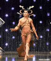 a man in a costume is standing in front of a black curtain with lights on it .