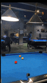 a group of people are playing pool on a blue table