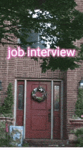 a red door with a wreath on it and a sign that says job interview above it