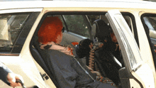 a woman with red hair is sitting in the back of a car