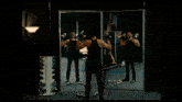 a man in a black tank top is lifting dumbbells in front of a mirror