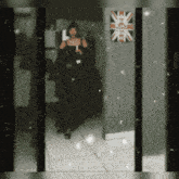 a woman in a black dress is walking through a hallway with a british flag on the wall
