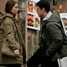 a man and a woman standing next to each other in front of a menu