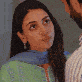 a woman in a green dress and blue scarf looks at a man