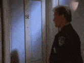 a police officer stands in front of a door that says 5e on it
