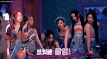a group of girls are standing around a pinball machine with the words honeycam.org written on the bottom