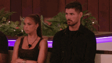 a man and a woman are sitting next to each other with their arms crossed and looking at something .