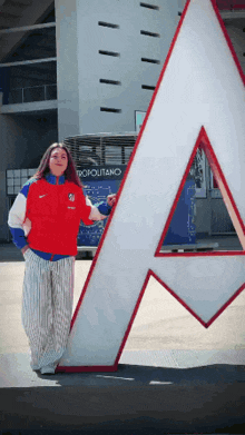 a woman in a red nike jacket stands next to a large a