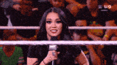a woman in a wrestling ring is holding a microphone and smiling .