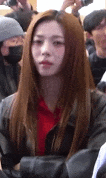 a woman with long red hair is wearing a red shirt and a black jacket