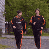 two men wearing fnatic jerseys are walking down a sidewalk