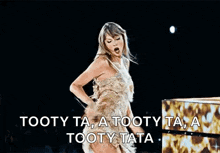 a woman in a gold dress is dancing on a stage with a microphone in her hand .