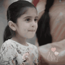 a little girl in a floral shirt is smiling with the name chris written below her