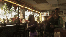 a man and woman are dancing in a bar with a sign that says budweiser on it