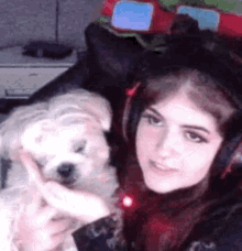 a girl wearing headphones is holding a small dog .