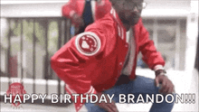 a man in a red jacket is dancing and says `` happy birthday brandon ! ''