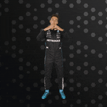 a man in a petronas jumpsuit is making a heart with his hands