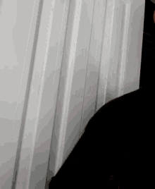 a person standing in front of a white wall with a black shirt on