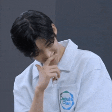 a young man wearing a white shirt with a pocket that says debut 's plan