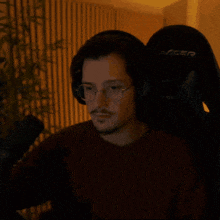 a man wearing headphones and glasses sits in a racer chair