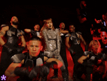 a group of people are dancing in a dark room with a purple flower in the background