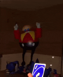 a person is playing uno with a sonic the hedgehog toy and a cartoon character .
