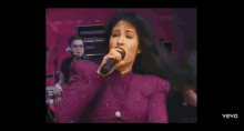 a woman is singing into a microphone on a stage .