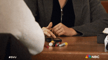 a nbc ad shows a woman sitting at a table with a bunch of pills on it