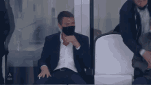 a man wearing a mask sits in a stadium with the letter a on the side