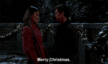 a man and a woman are standing next to each other and the man is saying merry christmas