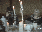 a woman sitting at a table with candles and a gif that says aespagifs on it