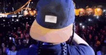 a man wearing a blue hat stands in front of a crowd of people