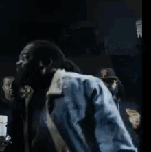 a man with a beard is standing in front of a crowd with a jacket on his back