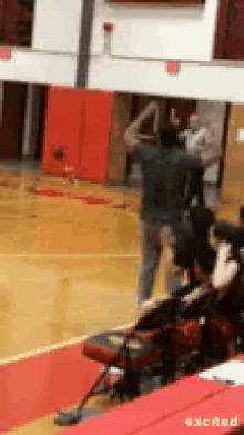 a man in a gray shirt is standing on a basketball court .