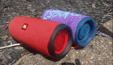 a red jbl speaker sits next to a purple speaker