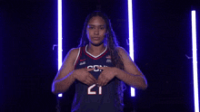 a woman wearing a uconn basketball jersey is pointing at the camera .
