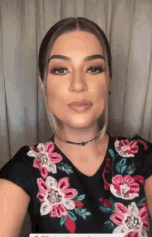 a woman wearing a choker and a floral shirt