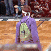 a man wearing a purple shirt and a green bag that says ows on it