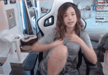a woman is sitting in a chair with a cat tree in the background and a sign that says " kneecap been doing "